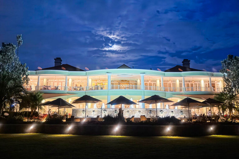 A brightly lit two-story building with balconies and outdoor seating, photographed at night under a cloudy, moonlit sky.